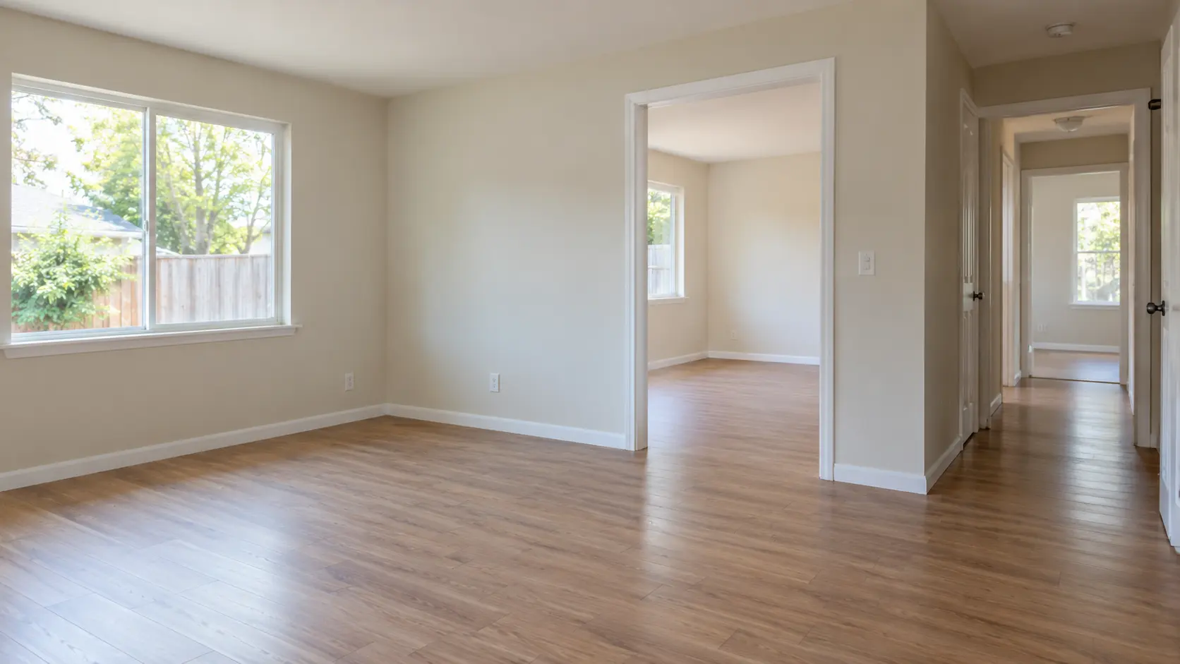 An unfurnished residential interior looking from the living room toward an adjoining hallway
